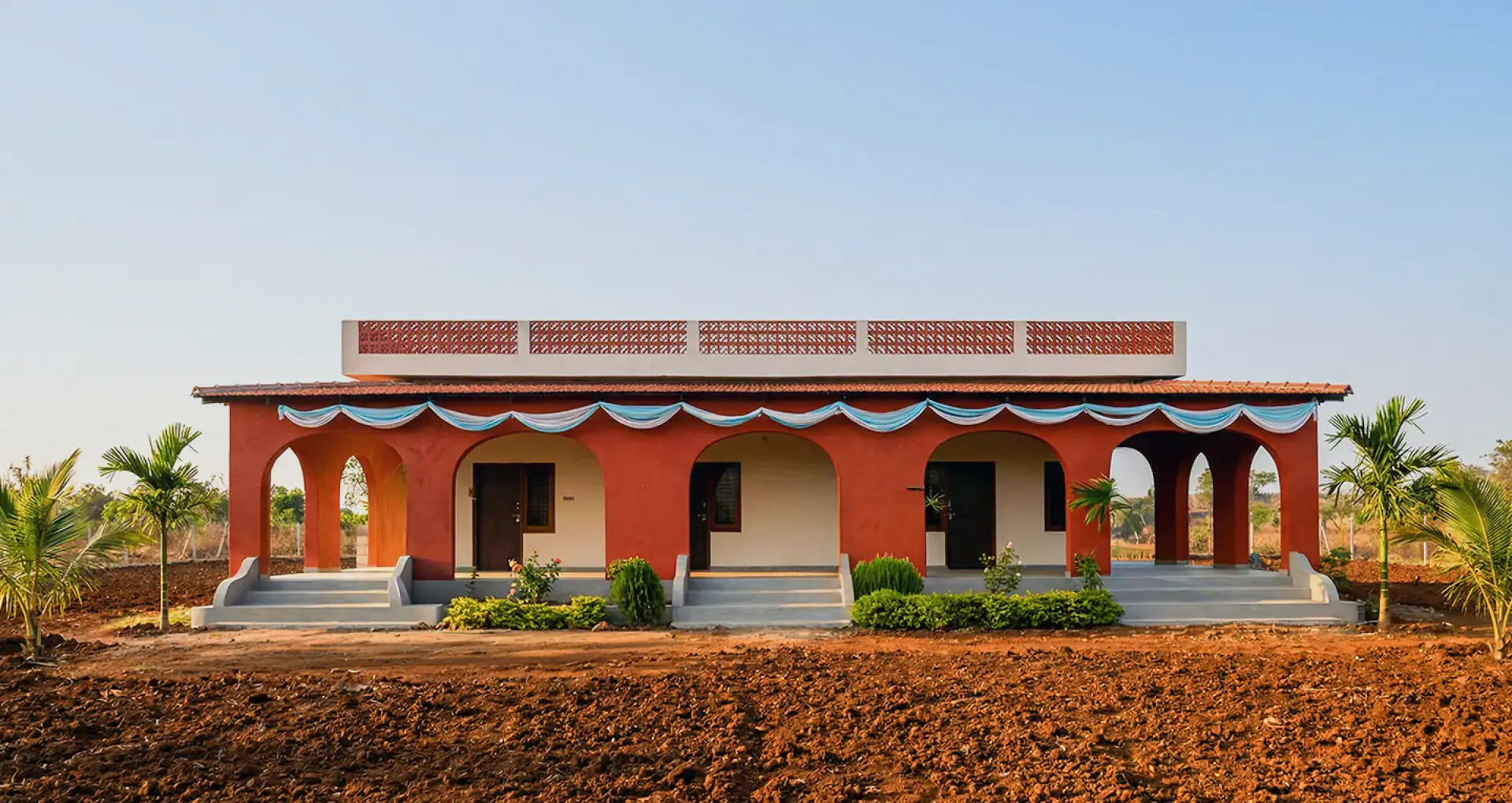 Vruksha, mud architecture set among planted rows